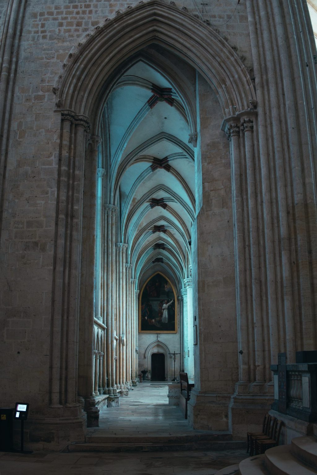 Perspective d'un bas-côté gothique de la cathédrale Notre-Dame de Sées, avec ses voûtes d'ogives et un tableau au fond
