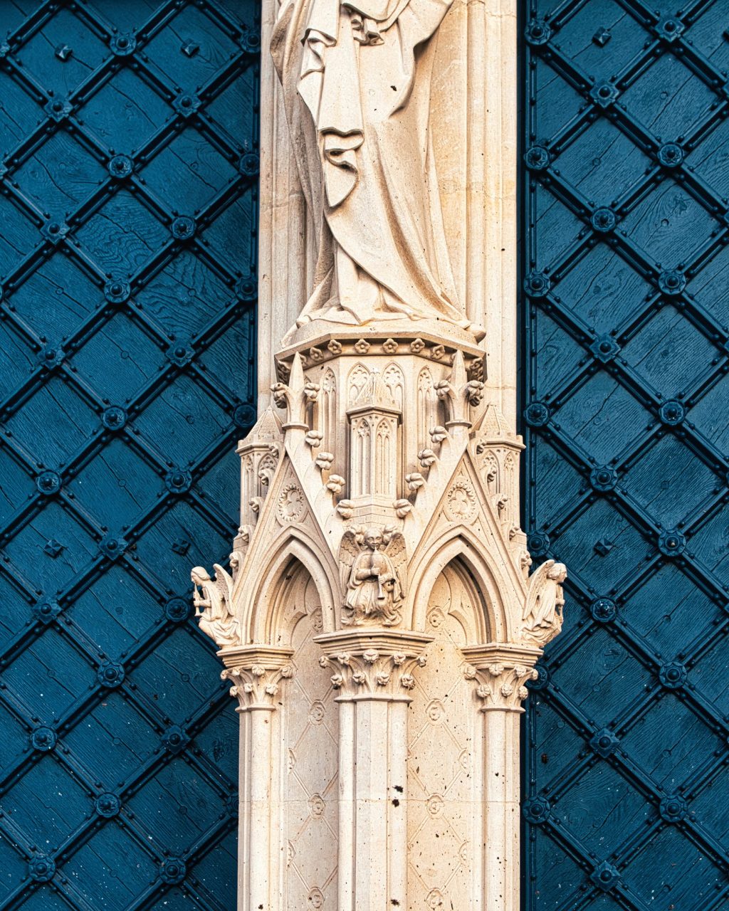 Trumeau sculpté portant une statue entre les vantaux bleus du portail de la cathédrale Notre-Dame de Sées