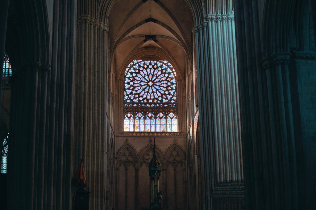 Rose à vitraux lumineuse dans la pénombre du transept de la cathédrale Notre-Dame de Sées