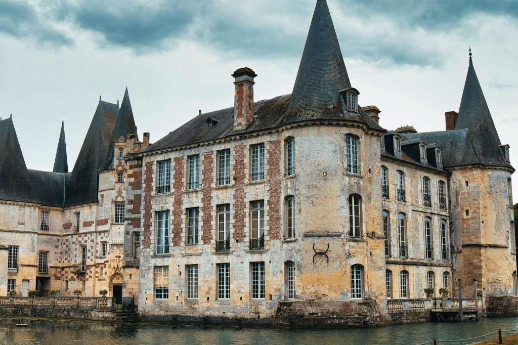 Le château d'Ô, ses tours coiffées d'ardoise et ses façades de brique et de pierre au bord des douves, à Mortrée dans l'Orne
