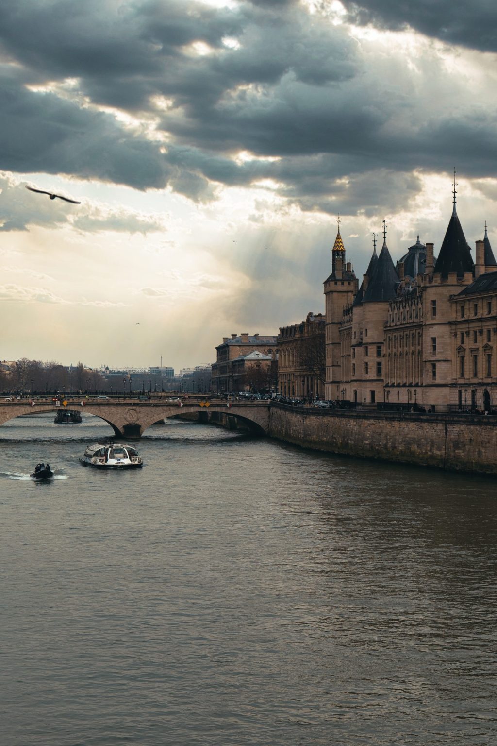 Tours de la Conciergerie au bord de la Seine sous un ciel d'orage percé de rayons de soleil, à Paris