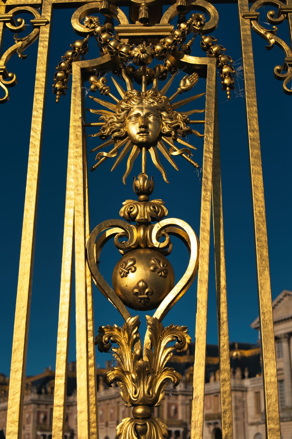 Détail doré de la grille royale du château de Versailles : masque d'Apollon rayonnant, emblème de Louis XIV, et globe fleurdelisé