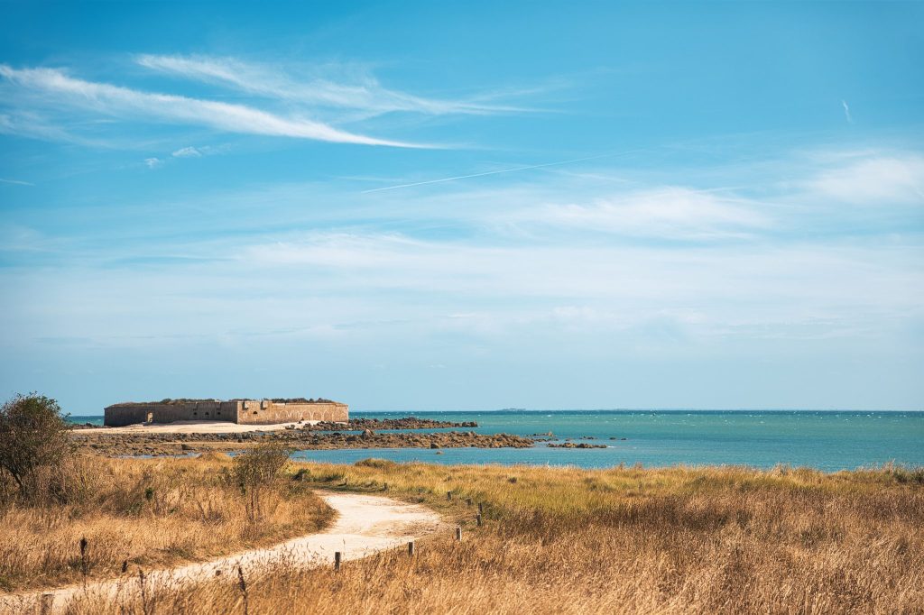 Sentier sablonneux à travers les herbes sèches menant vers des fortifications au bord de la mer, sur l'île Tatihou