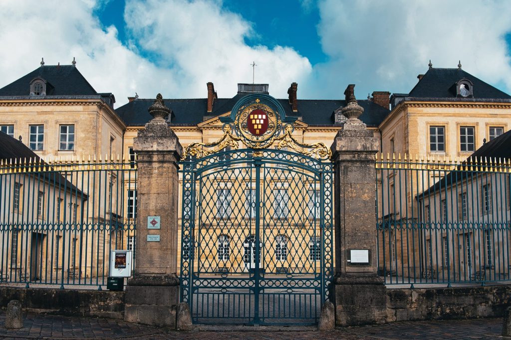 Grille en fer forgé aux armoiries dorées et façade classique du palais d'Argentré, ancien palais épiscopal de Sées