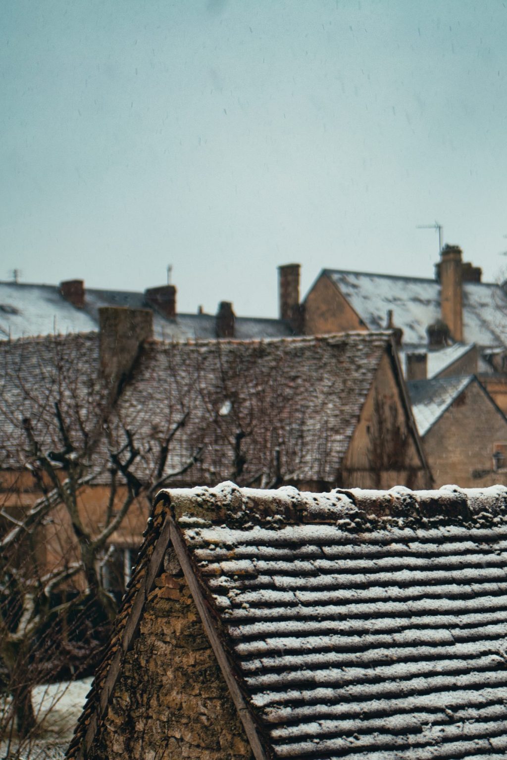 Toits de tuiles anciennes et cheminées de Sées couverts d'une fine couche de neige