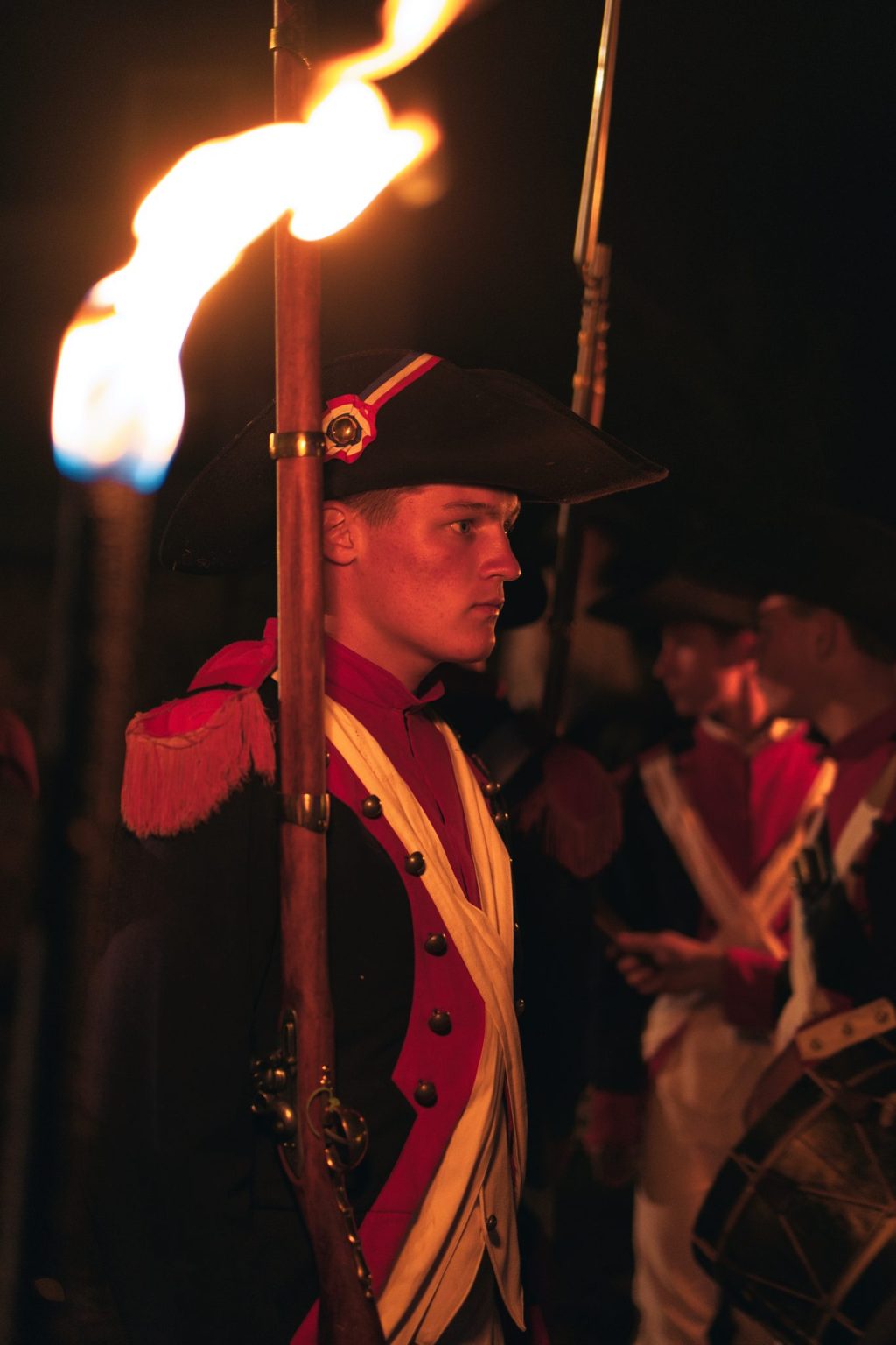 Jeune comédien en uniforme de soldat républicain, coiffé d'un bicorne, éclairé par une torche lors du spectacle de Siècles en scène à Sées
